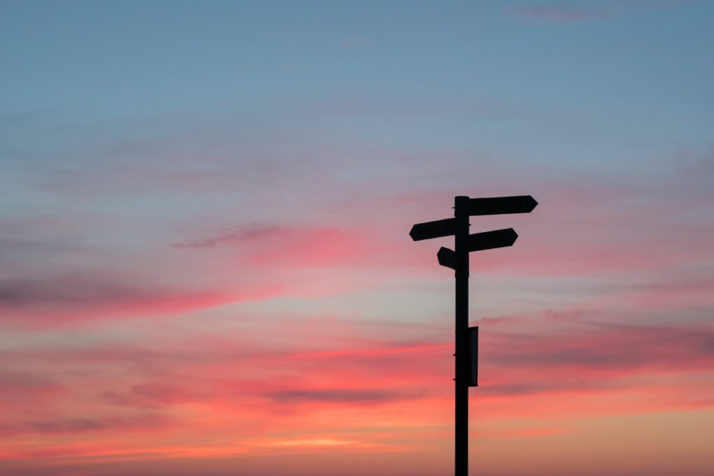 Directional sign in front of a sunset