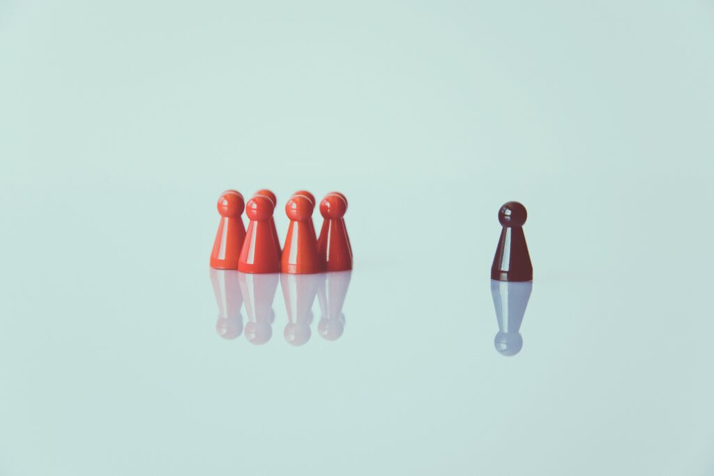 A group of red chess pawns with one black pawn on the outside